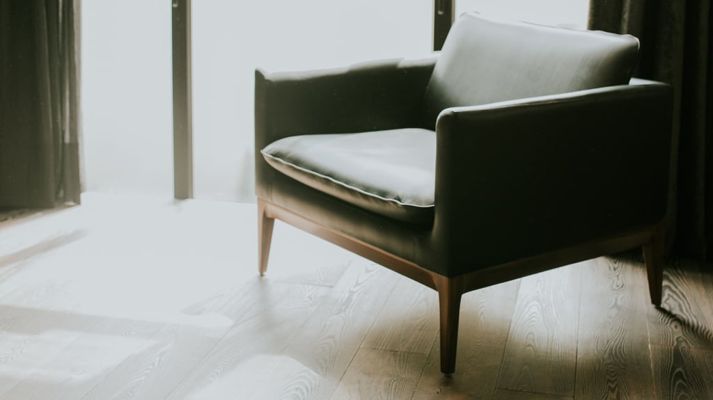 Dark leather armchair on a light wooden floor in front of a bright window